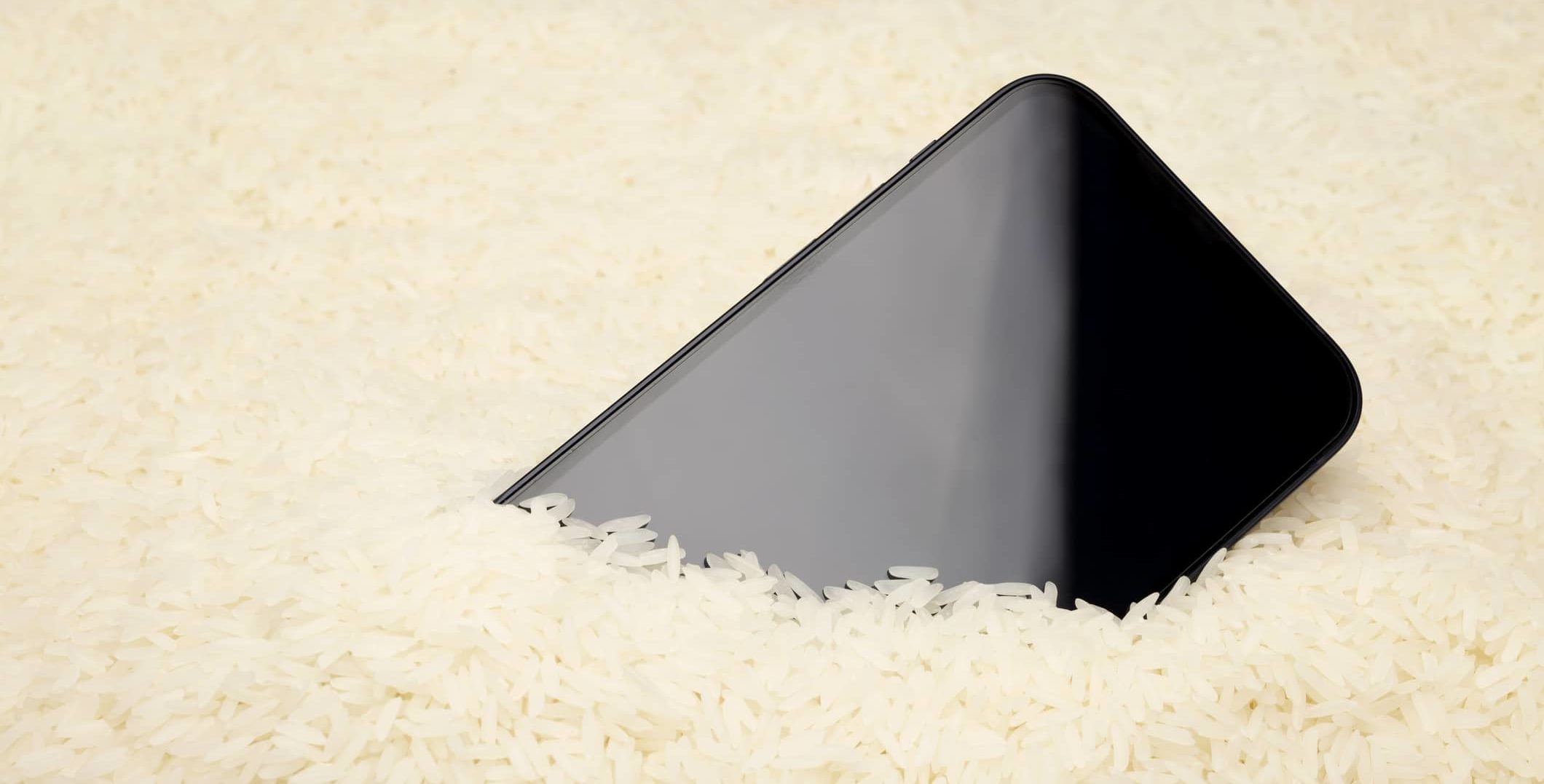 a-wet-smartphone-is-dried-in-raw-rice-on-white-background