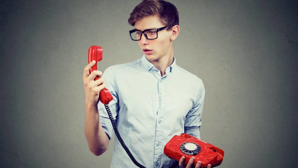 confused-teenager-man-looking-at-old-fashioned-telephone