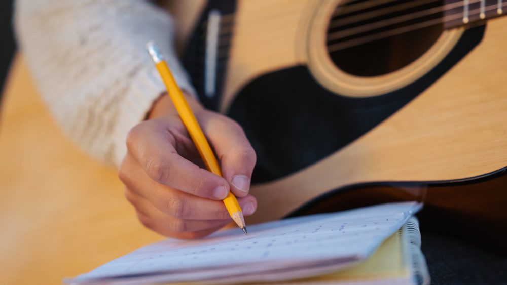 close-up-of-a-girl-musician-composing-song-writing-down-chords-to-the-notes