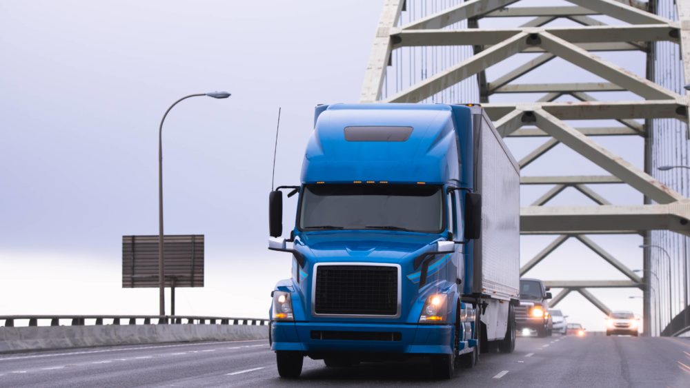 blue-big-rig-semi-truck-transporting-semi-trailer-on-arched-fremont-bridge