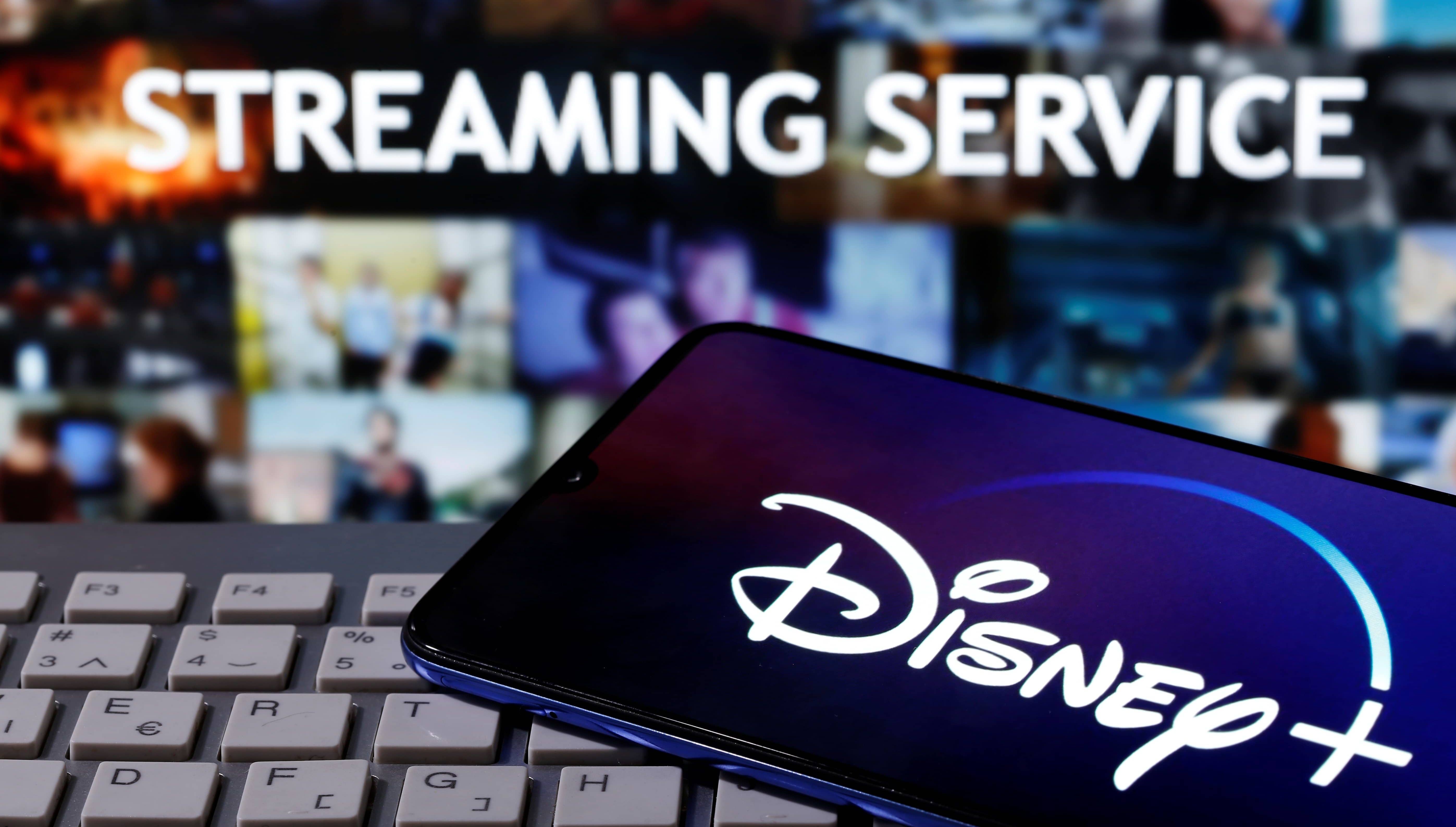 smartphone-with-displayed-disney-logo-is-seen-on-the-keyboard-in-front-of-displayed-streaming-service-words-in-this-illustration