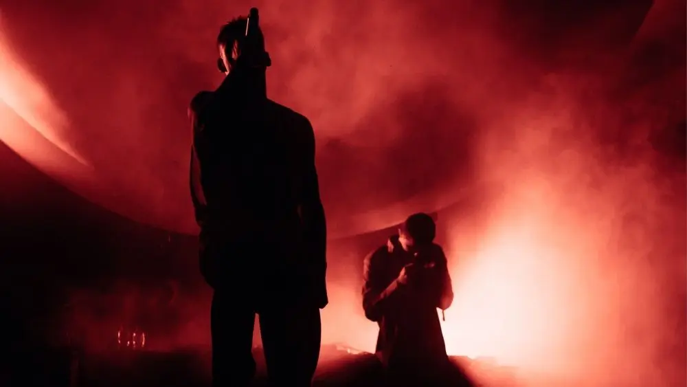 Silhouettes of two singers in the smoke. Red Illumination. Man sings on the stage.