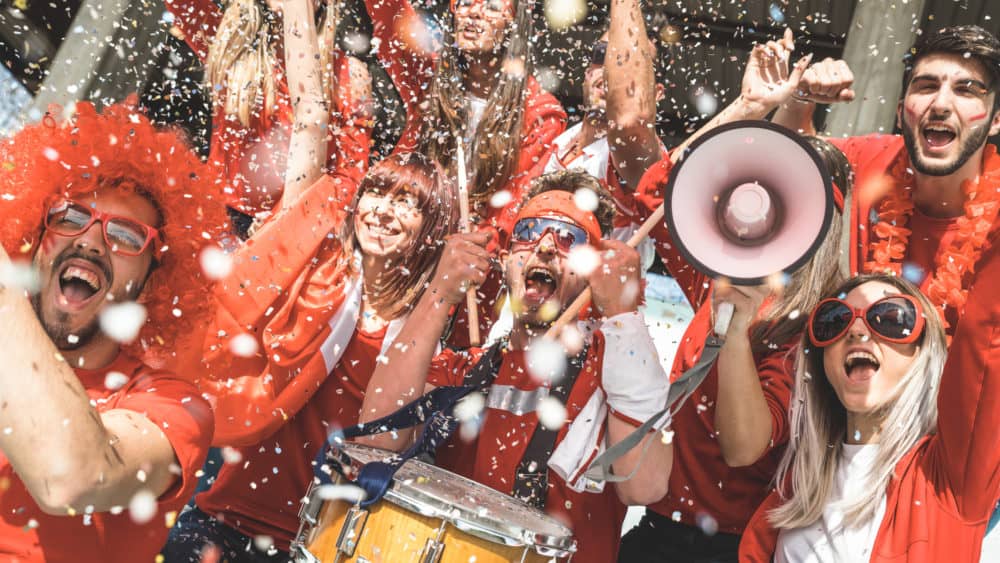 friends-football-supporter-fans-cheering-with-confetti-watching-soccer-match-event-at-stadium-young-people-group-with-red-t-shirts-having-excited-fun-on-sport-world-championship-concept