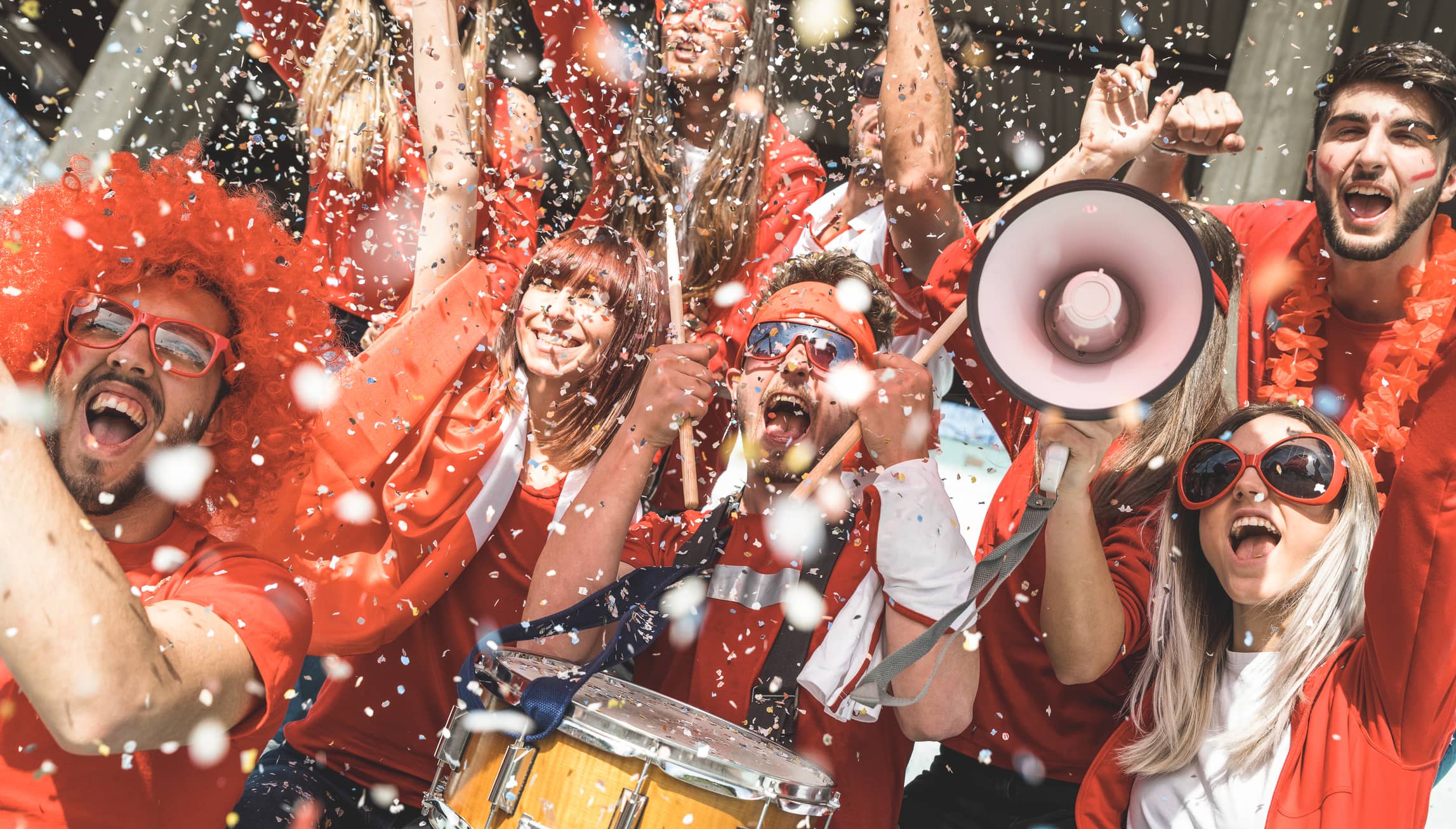 friends-football-supporter-fans-cheering-with-confetti-watching-soccer-match-event-at-stadium-young-people-group-with-red-t-shirts-having-excited-fun-on-sport-world-championship-concept