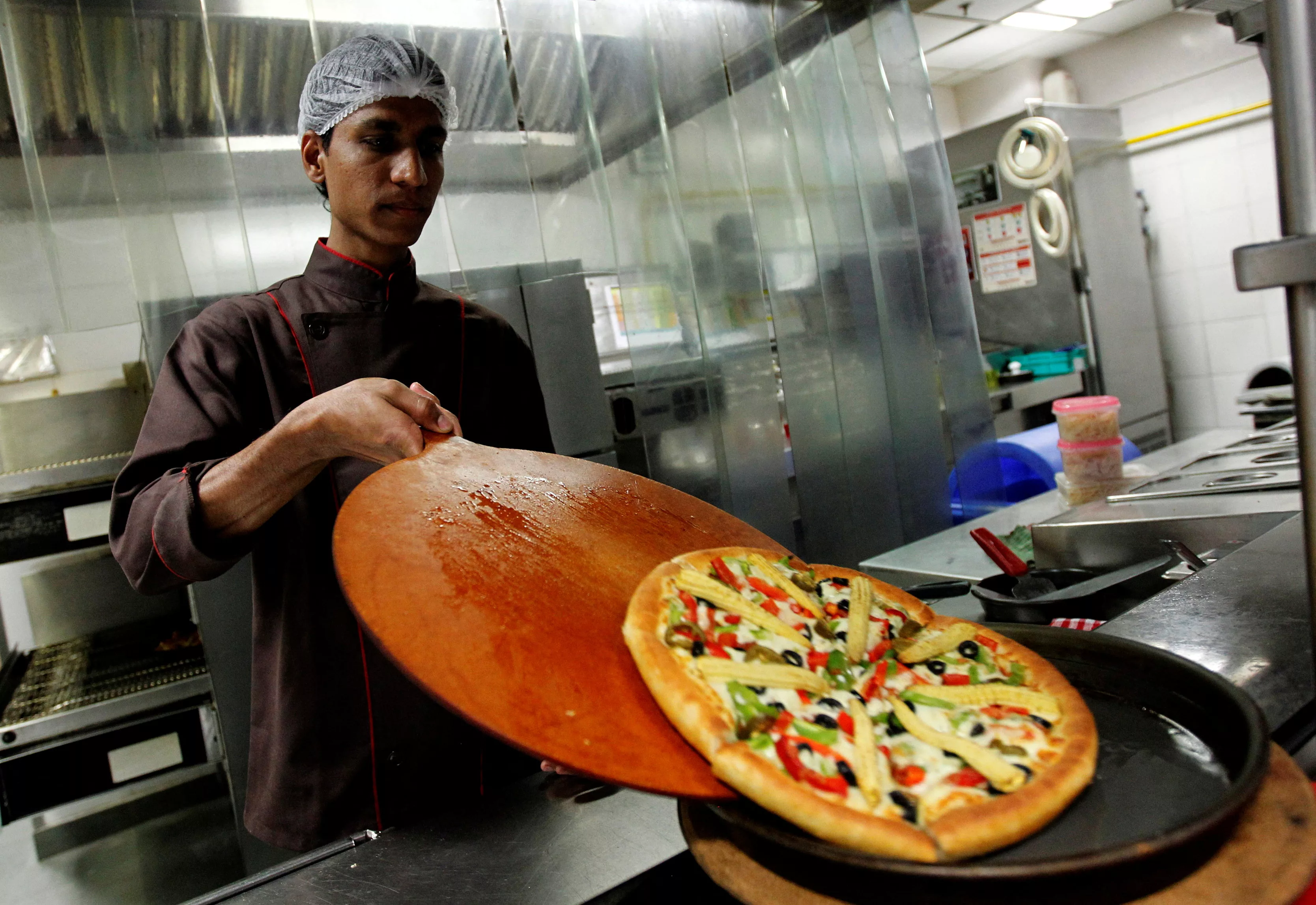 file-photo-a-cook-slides-a-pizza-onto-a-serving-plate-in-the-kitchen-at-a-pizza-hut-restaurant-in-mumbai-march-29-2011