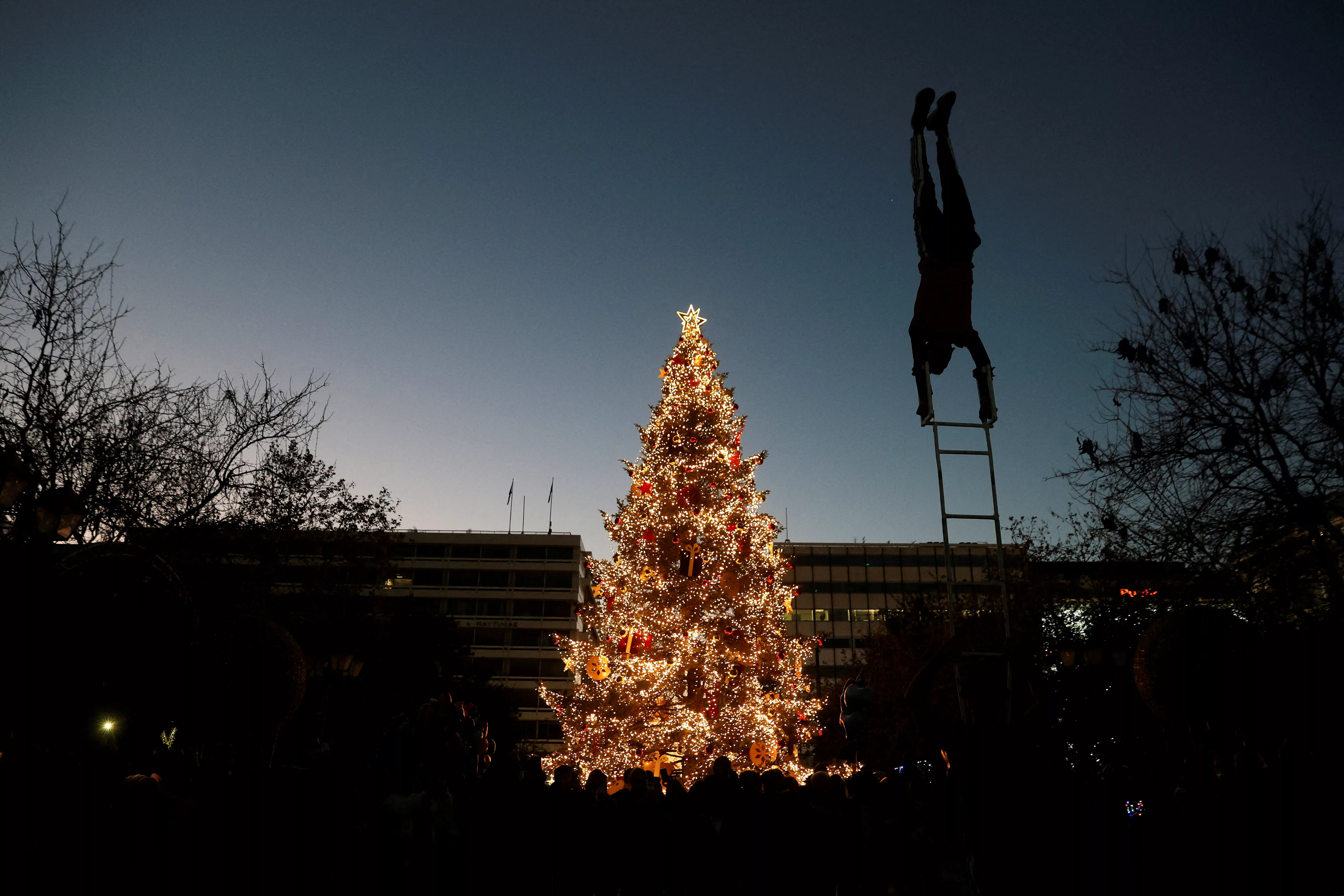 a-street-artist-performs-in-front-of-the-christmas-tree-at-syntagma-square-during-christmas-festivities-in-athens