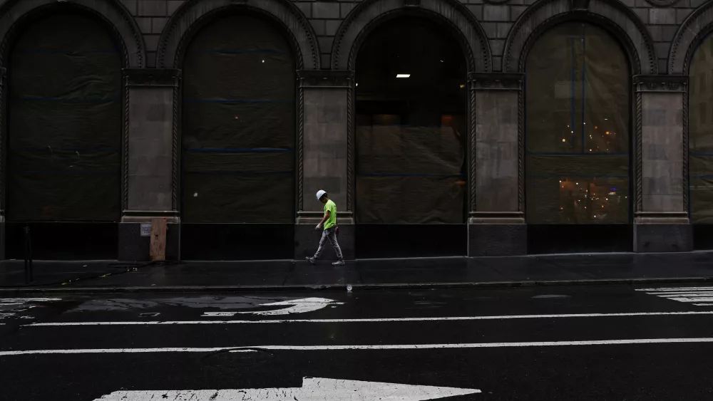 a-man-walks-on-the-sidewalk-by-a-building-construction-site-in-the-midtown-neighborhood-of-new-york-city