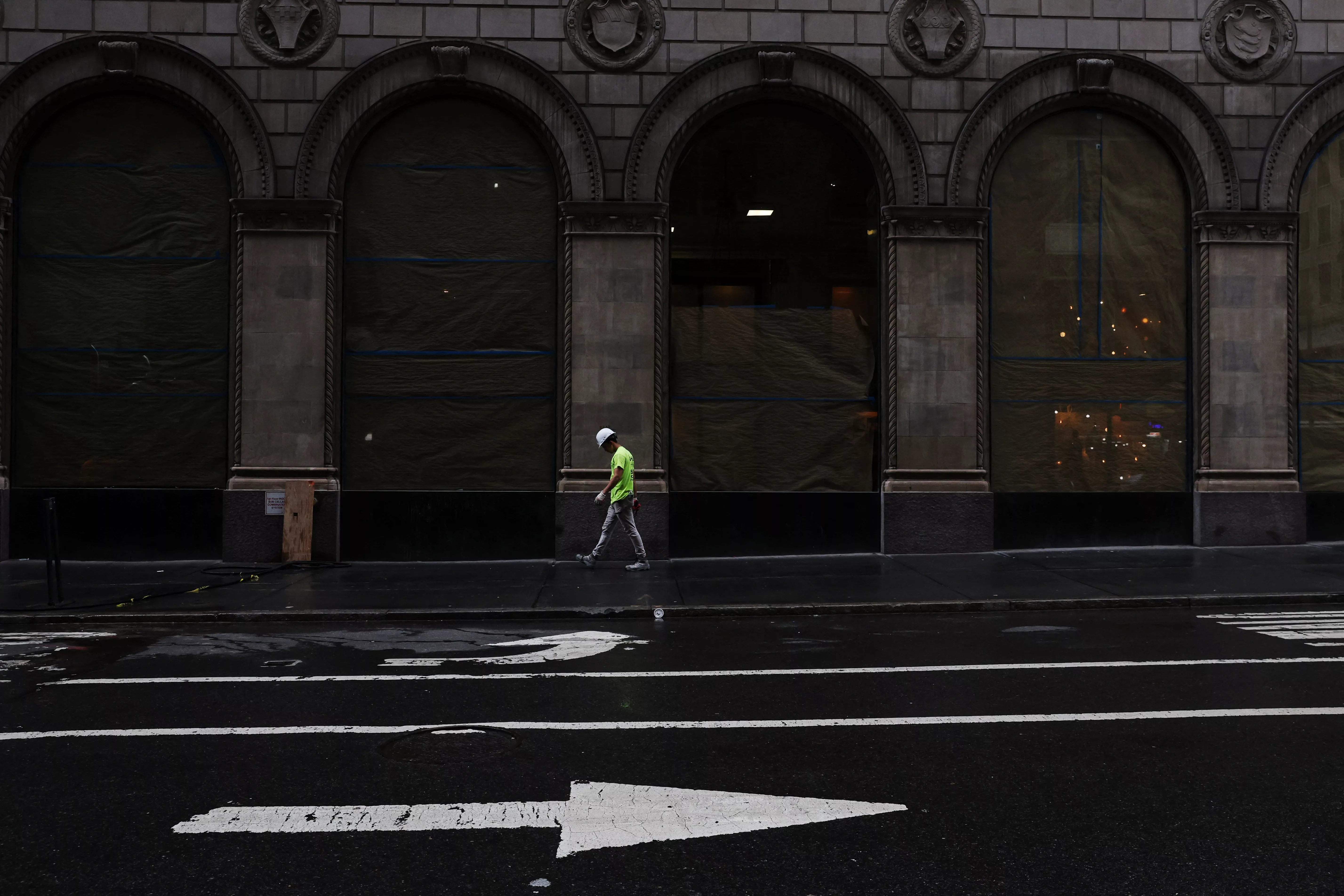 a-man-walks-on-the-sidewalk-by-a-building-construction-site-in-the-midtown-neighborhood-of-new-york-city
