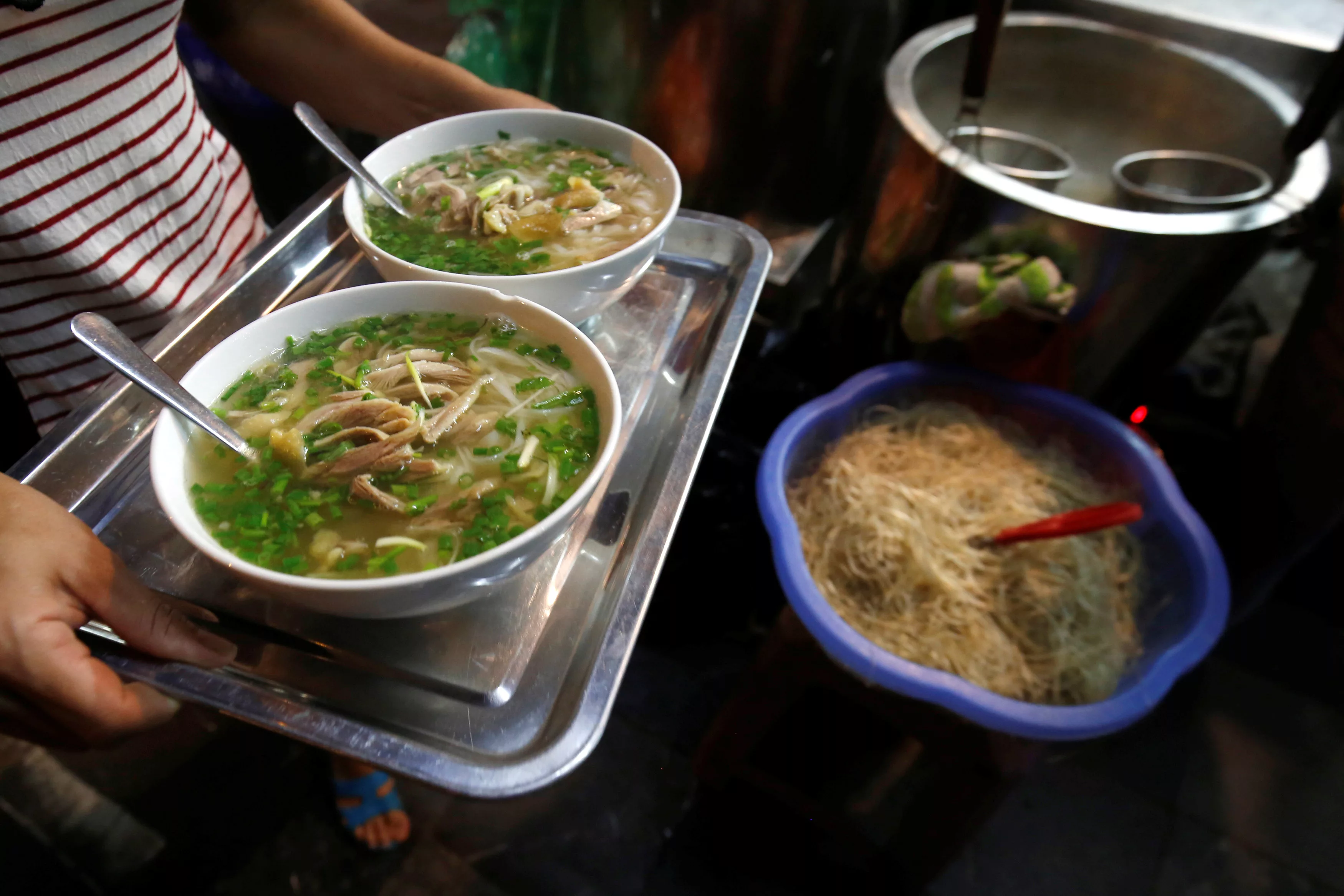 a-woman-carries-bowls-of-vietnamese-chicken-noodle-soup-pho-at-a-restaurant-in-hanoi