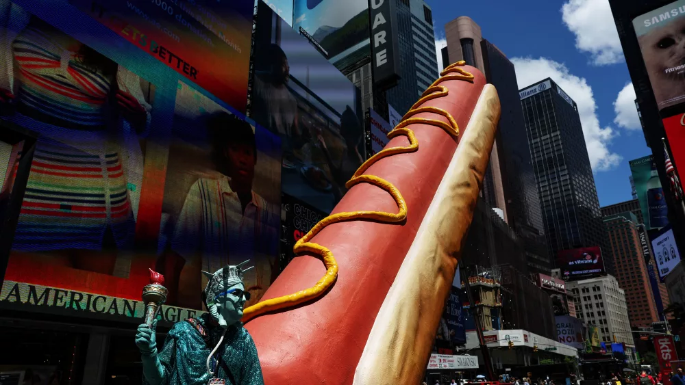 a-man-dressed-as-the-statue-of-liberty-stands-next-a-giant-hot-dog-in-the-times-square-area-in-new-york-city