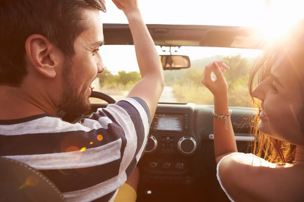 young-couple-driving-along-country-road-in-open-top-car