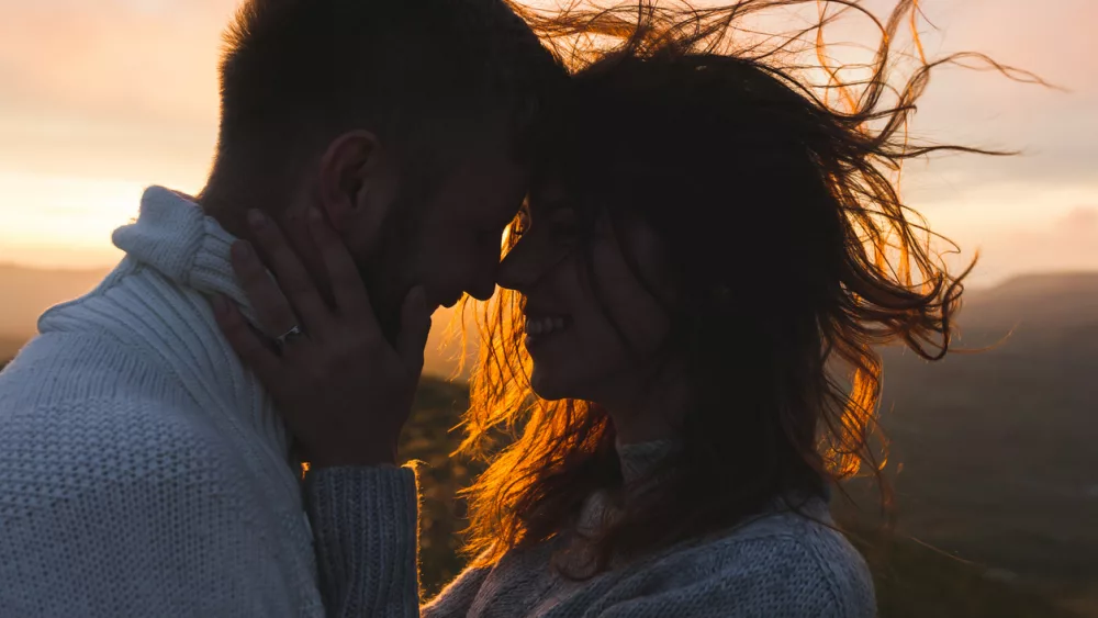 gentle-close-up-portrait-of-man-and-woman-together-happy-looking-at-each-other-silhouette-at-beautiful-sunset-light-wind-in-hair
