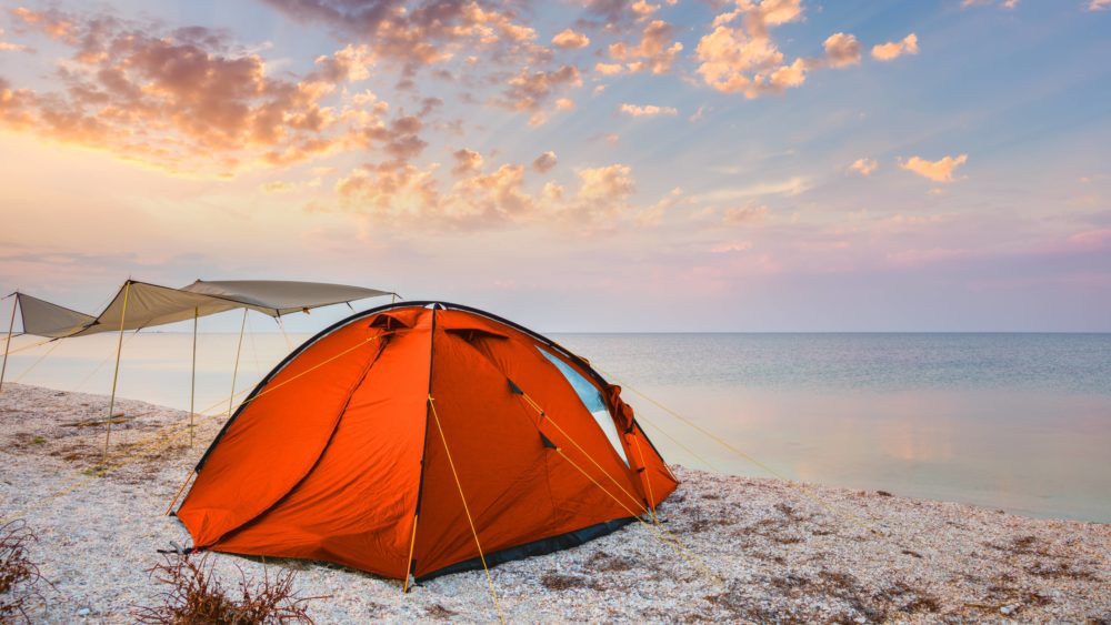 camping-tent-on-a-beautiful-quiet-beach-near-the-water-against-the-sunset-sky-background-happy-summer-time