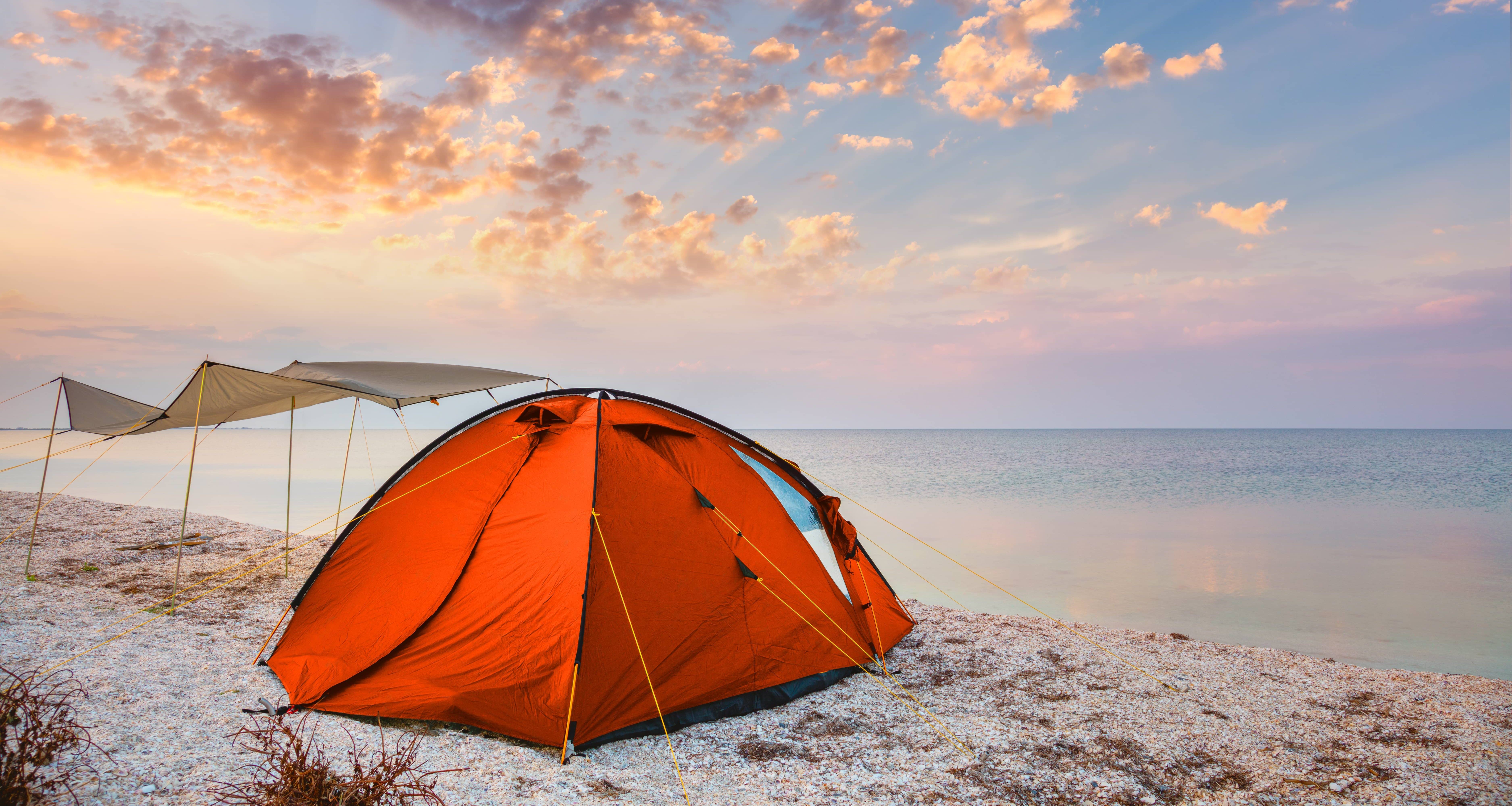 camping-tent-on-a-beautiful-quiet-beach-near-the-water-against-the-sunset-sky-background-happy-summer-time