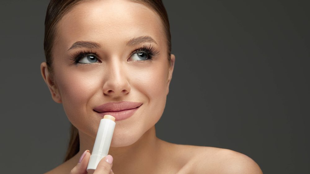 lips-skin-care-beautiful-woman-face-with-lips-applying-hygienic-lip-balm-lip-care-stick-closeup-of-female-face-with-soft-skin-putting-lip-protector-lipstick-on-beauty-cosmetics-concept