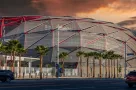 The Intuit Dome with cars driving on the street^ lush green palm trees and powerful clouds at sunset in Inglewood California USA. Inglewood^ California USA - 10 22 2024