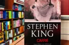 Paperback cover of Carrie by Stephen King shown on a bookshop shelf background