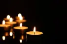 Burning candles on mirror surface in darkness^ closeup