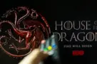 House of the Dragon HBO TV series on TV with remote control in hand. Focuse on the tv screen. Story takes place 300 years before events portrayed in Game of Thrones