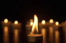 Burning candles. The candles burn against a black background and the flames move when the wind blows. The concept of a memorial day. Background for advertising and design projects.
