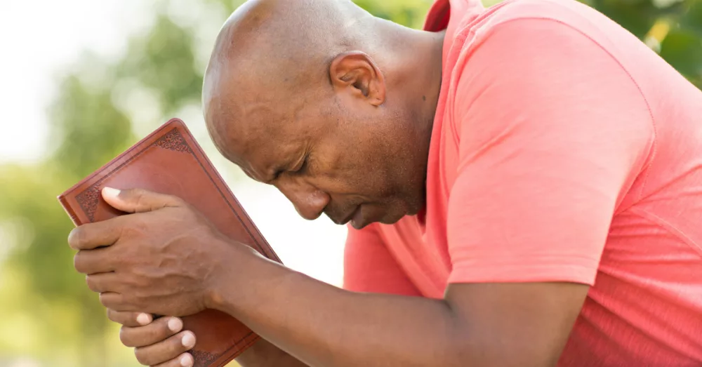 5922-man-praying-holding-bible-eyes-closed-gettyim383115