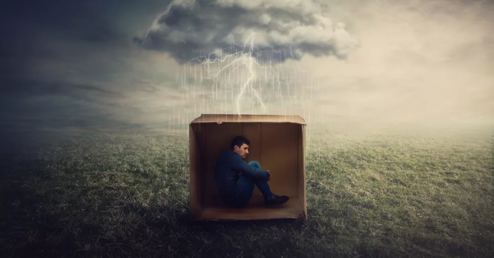 16507-scared-man-hiding-in-cardboard-box-in-storm-u504549