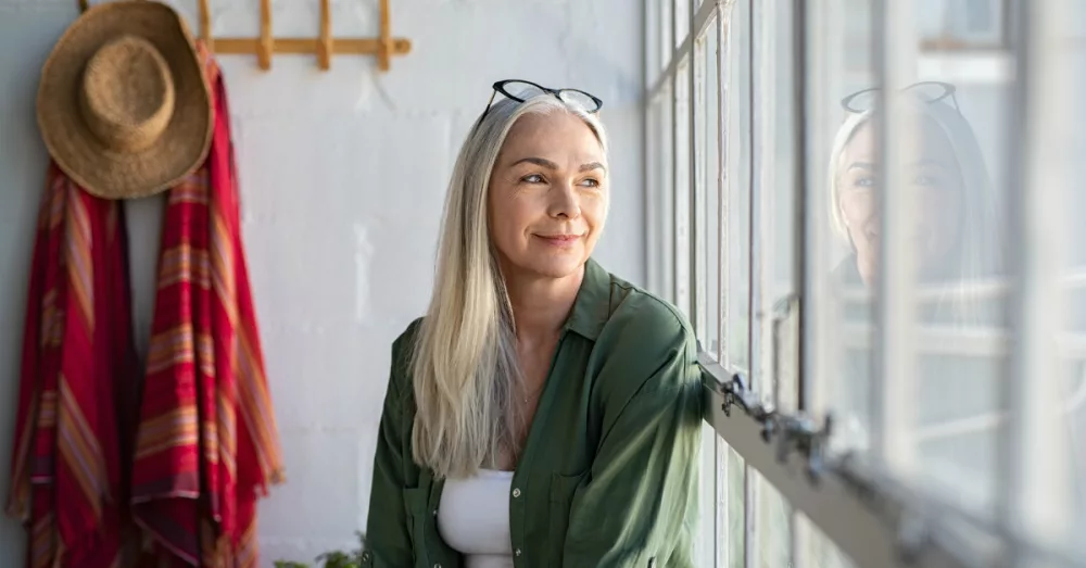 10387-senior-woman-looking-out-window-smiling-getty531854