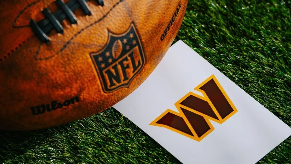 Washington Commanders NFL team Logo and American football ball on Green Grass.