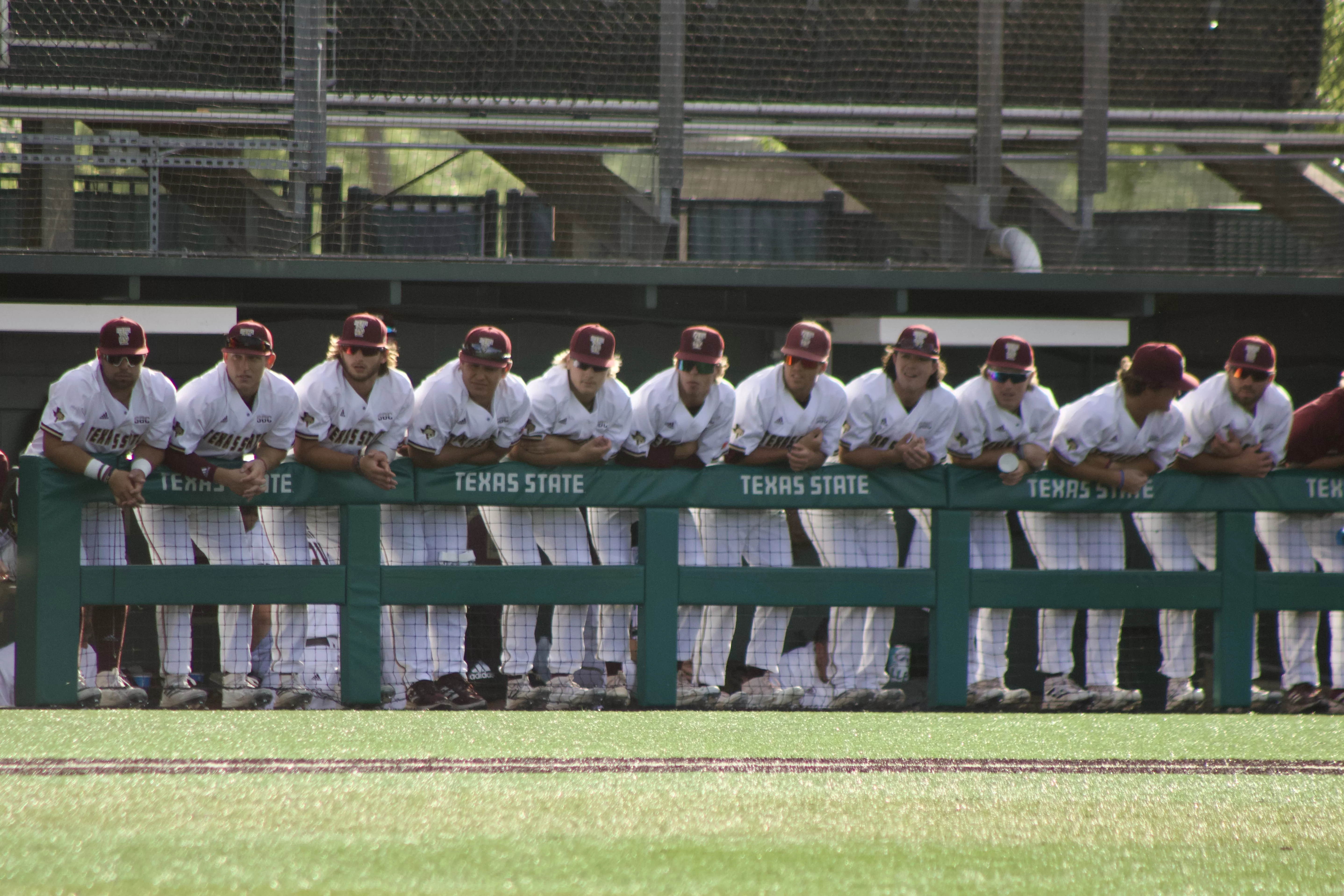 The Texas State Baseball team leaning against the dugout at Bobcat Ballpark Image by: Kyle Owen