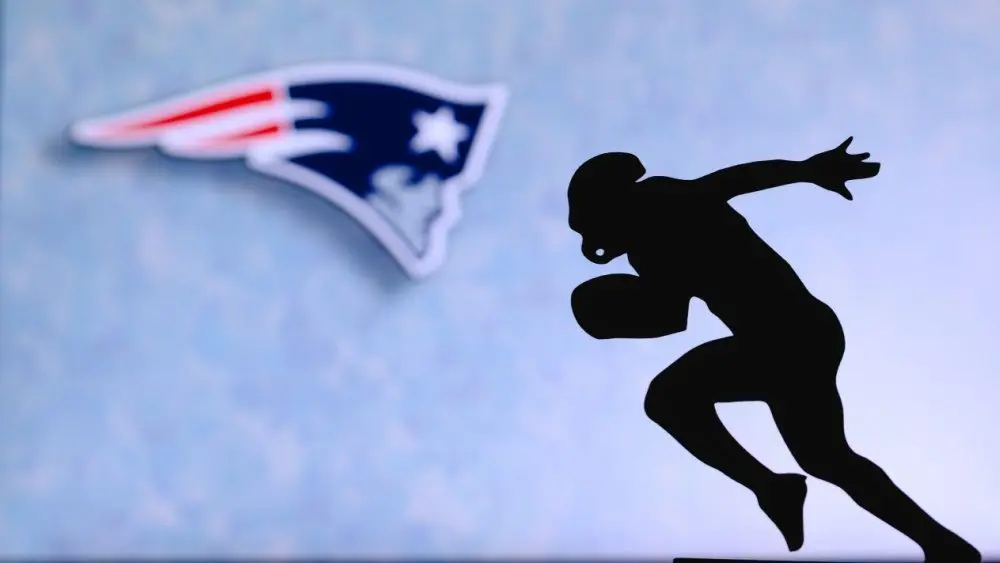 New England Patriots. Silhouette of professional american football player. Logo of NFL club in background^ edit space.
