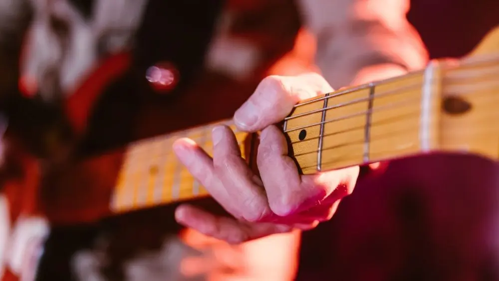 Close up look of a man playing the electric guitar during a concert^ no faces are shown^ shallow depth of field