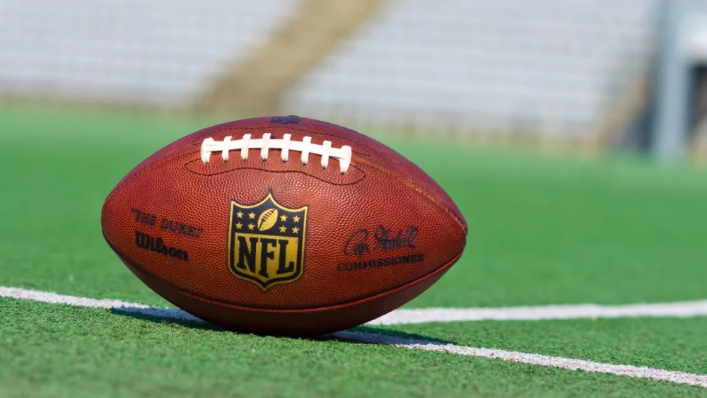 Official ball of the NFL football league on grass turf background.