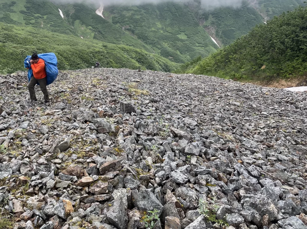 Adam Bucki hauls a load of trash from Fireweed rock glacier to the site where a helicopter will pick it up and haul it back to nearby McCarthy. He would later dispose of the trash in a sanitary landfill. Photo by Ned Rozell.
