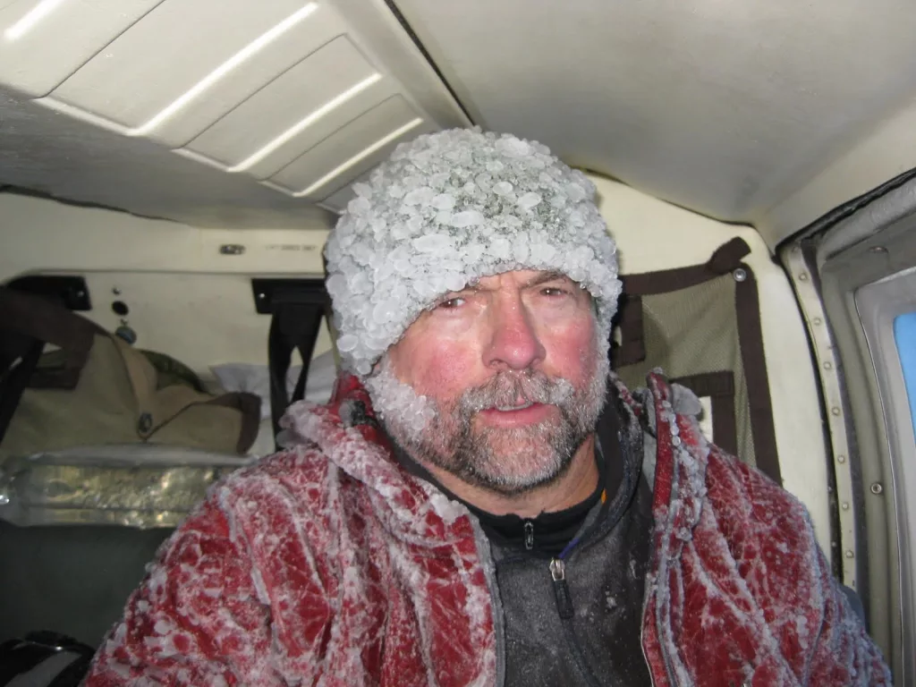 Volcano researcher John Paskievitch sits down coated in ice after three hours of creating and securing anchor points to tie off a Jet Ranger helicopter stranded by ice on the summit of Mount Mageik in the Valley of 10,000 Smokes. Photo by Taryn Lopez.