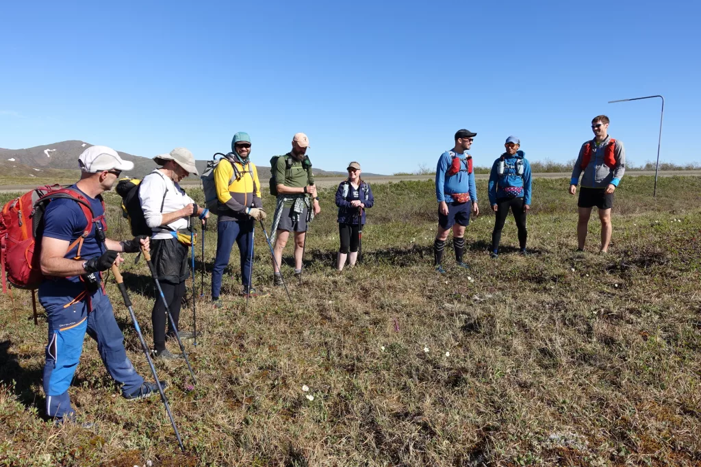 Competitors in the AlaskAcross 2024 race prepare to depart from Eagle Summit at 10 a.m. on June 8, 2024. From left are Bruno Grunau, Mark Ross, Forest Wagner, Mike Fisher, Sarah Hurkett, Clinton Brown, Tracie Curry and Curtis Henry. Photo by Ned Rozell.