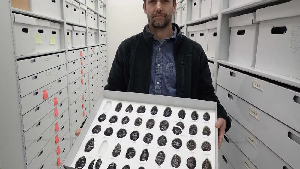 Archaeologist Jeff Rasic holds a tray of obsidian tools found in the Nogahabara Dunes west of the Koyukuk River. Photo by Ned Rozell.