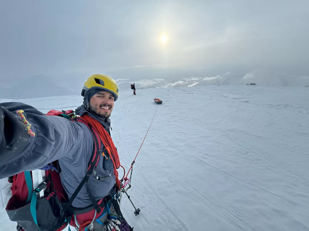  Roger Jaramillo walks on crampons while roped to a sled and his partner Matthew Crisafi-Lurtsema. The pair climbed Denali and sampled microplastics along their route in June, 2024. Photo by Roger Jaramillo.