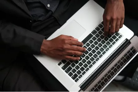 Hands typing on a laptop