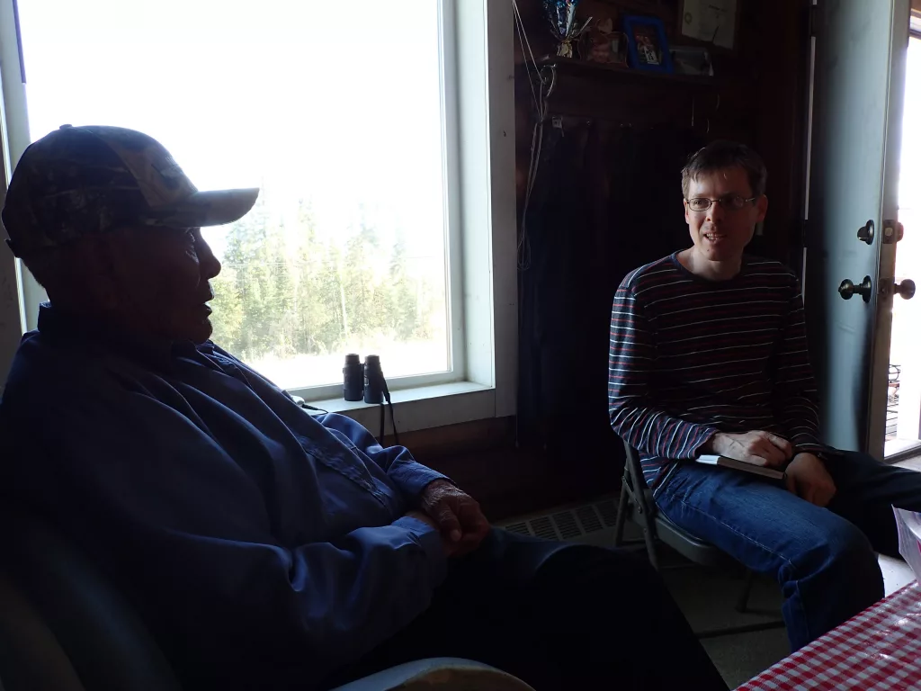 . In Minto, Alaska, UAF seismologist Carl Tape listens to the late Berkman Silas in 2014. Silas remembered a large earthquake he experienced in 1937. Photo by Ned Rozell.