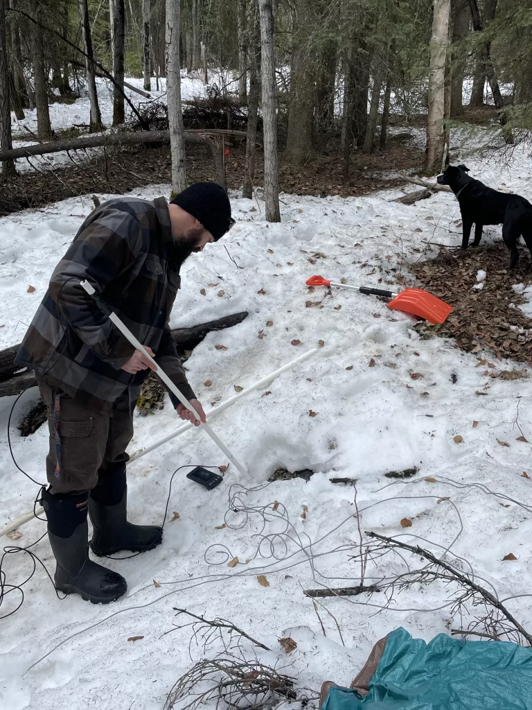 Colby Wright of the University of Alaska Fairbanks Geophysical Institute extends a camera into a sinkhole that developed in the northeast corner of campus. Photo by Ned Rozell.
