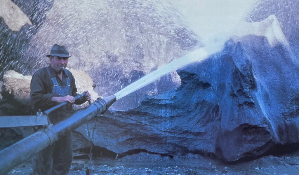 In 1979, gold miner Walter Roman stands with his “monitor” hose used to strip away soil and vegetation. Photo by Dale Guthrie.