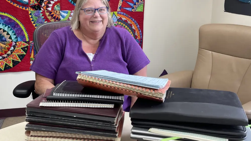 In June 2025, Kathe Rich sits in her office at Poker Flat Research Range behind notebooks she has filled with details of her 35 years at the rocket-launching facility. Photo by Ned Rozell.