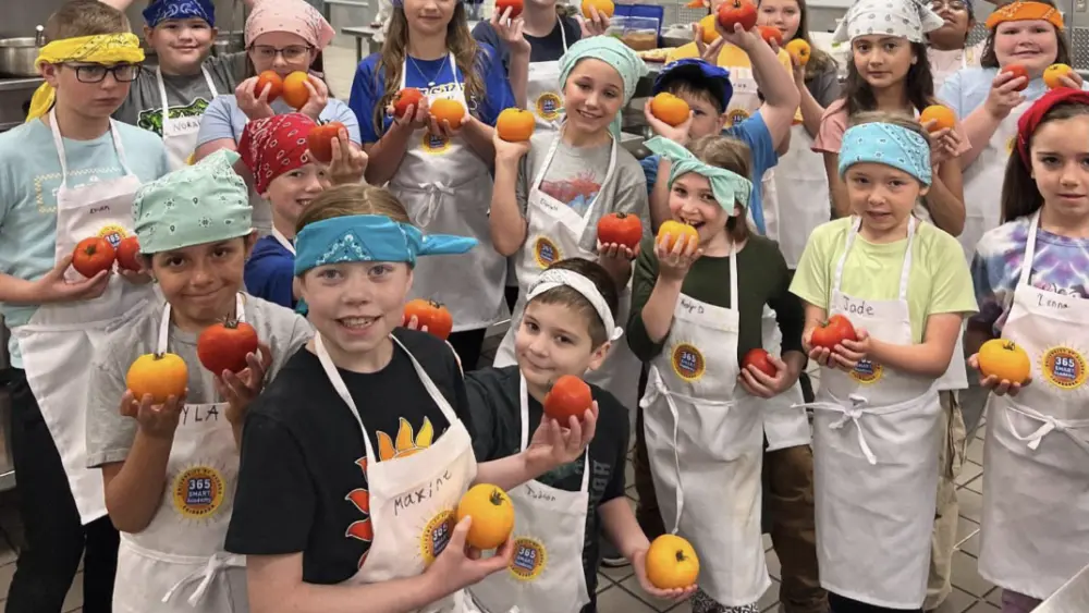Students participating in the UAF Summer Sessions Baking Blitz Camp hold up tomatoes grown as part of an experiment to optimize greenhouse productivity. Photo by Sean Walklin