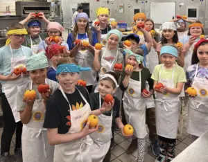 Students participating in the UAF Summer Sessions Baking Blitz Camp hold up tomatoes grown as part of an experiment to optimize greenhouse productivity. Photo by Sean Walklin