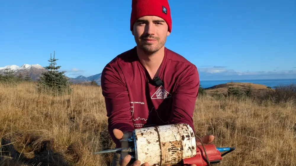 University of Alaska Fairbanks doctoral student Cade Quigley holds a freshly unearthed seismic sensor in Kodiak in November 2025. Photo by Sara Wilbur