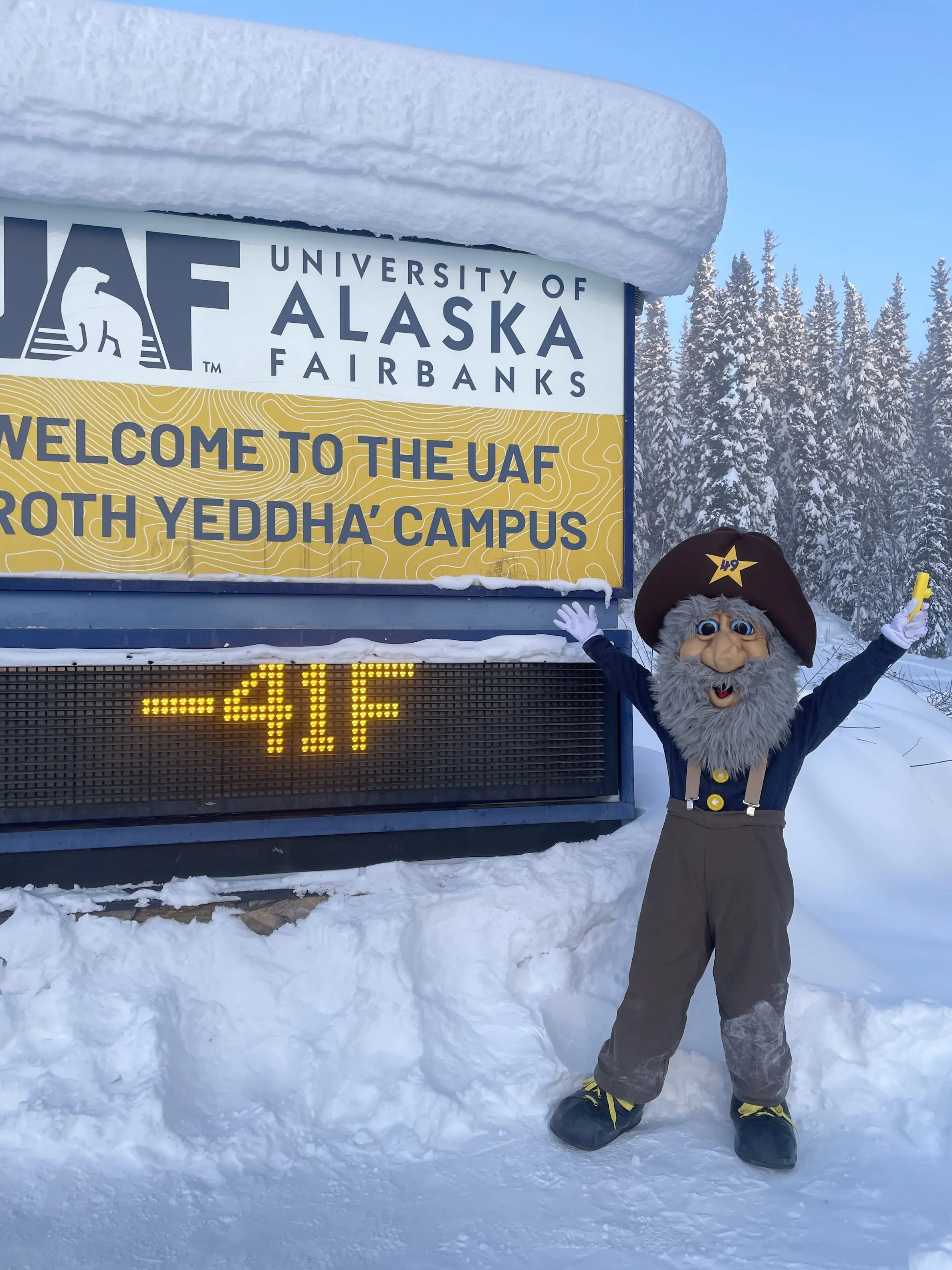 2. Alaska Goldpanners baseball team mascot Happy Boy (aka Chris Carlson of Fairbanks) poses in front of the University of Alaska Fairbanks temperature sign on the morning of March 1, 2026. Photo by Ned Rozell.