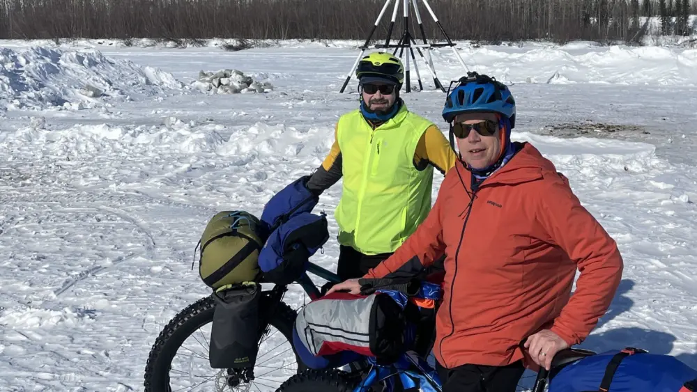 Forest Wagner, left, and Ned Rozell pause in front of the tripod on the ice of the Tanana River at the town of Nenana. When river ice breaks up, whoever guesses the exact time the tripod falls and pulls a cable will be the winner of the Nenana Ice Classic. Photo by Ned Rozell.