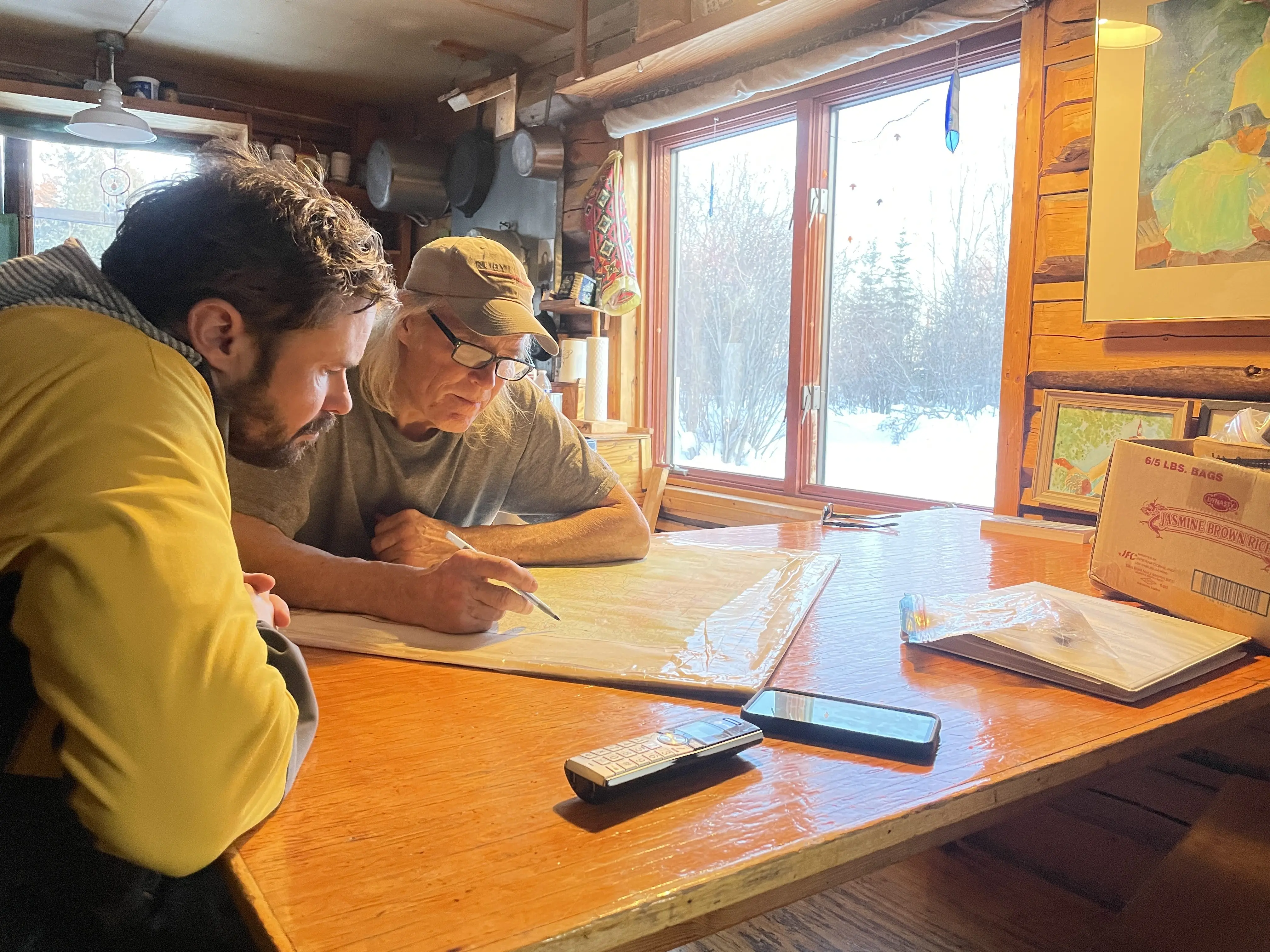 Forest Wagner, left, and Charlie Campbell of Tanana confer over a map at Campbell’s house in Tanana. Photo by Ned Rozell.