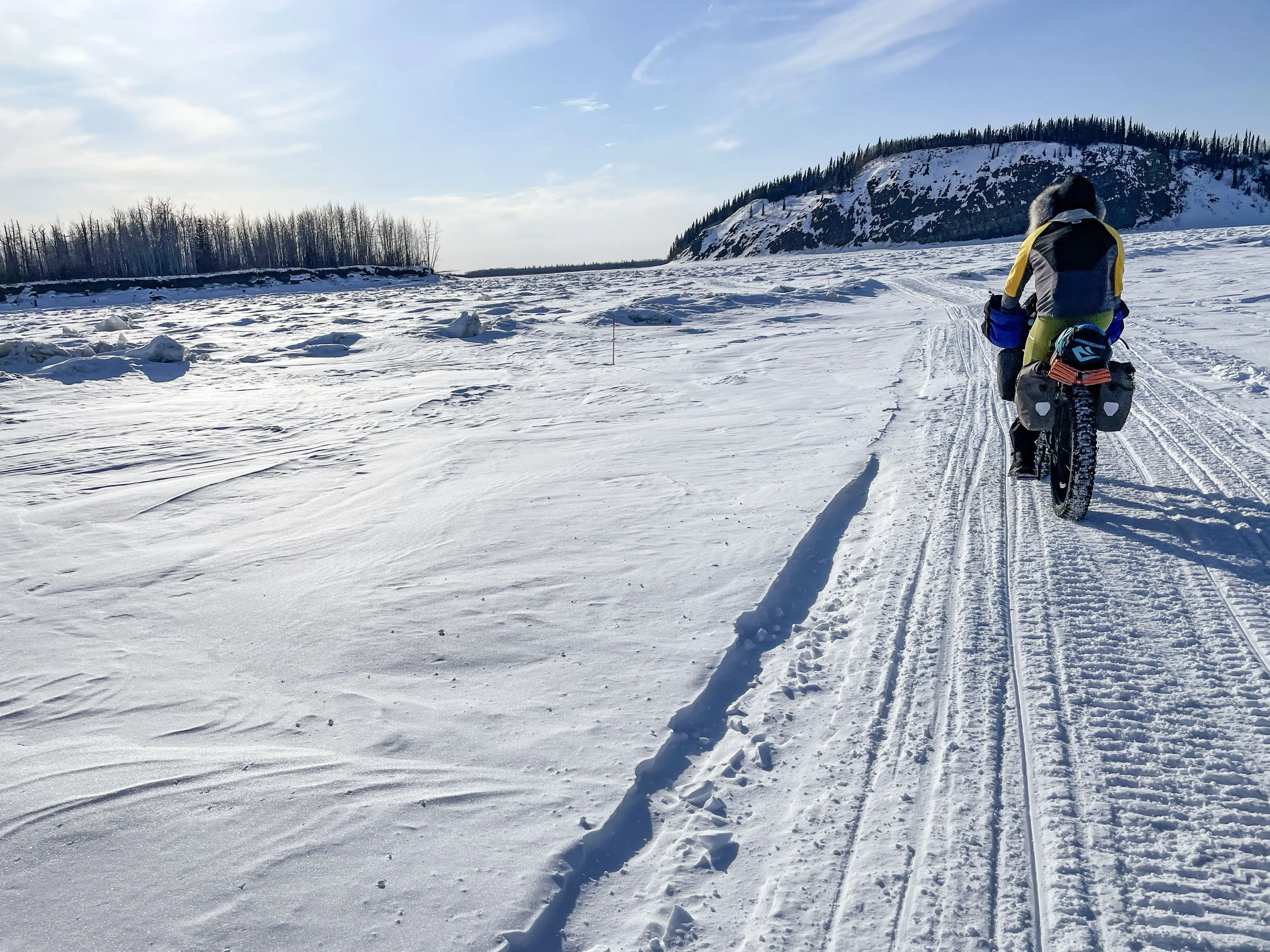 Forest Wagner rides his fat bike near Bishop Rock, right, a pinch point on the flow of the Yukon River, on April 5, 2026. Photo by Ned Rozell.
