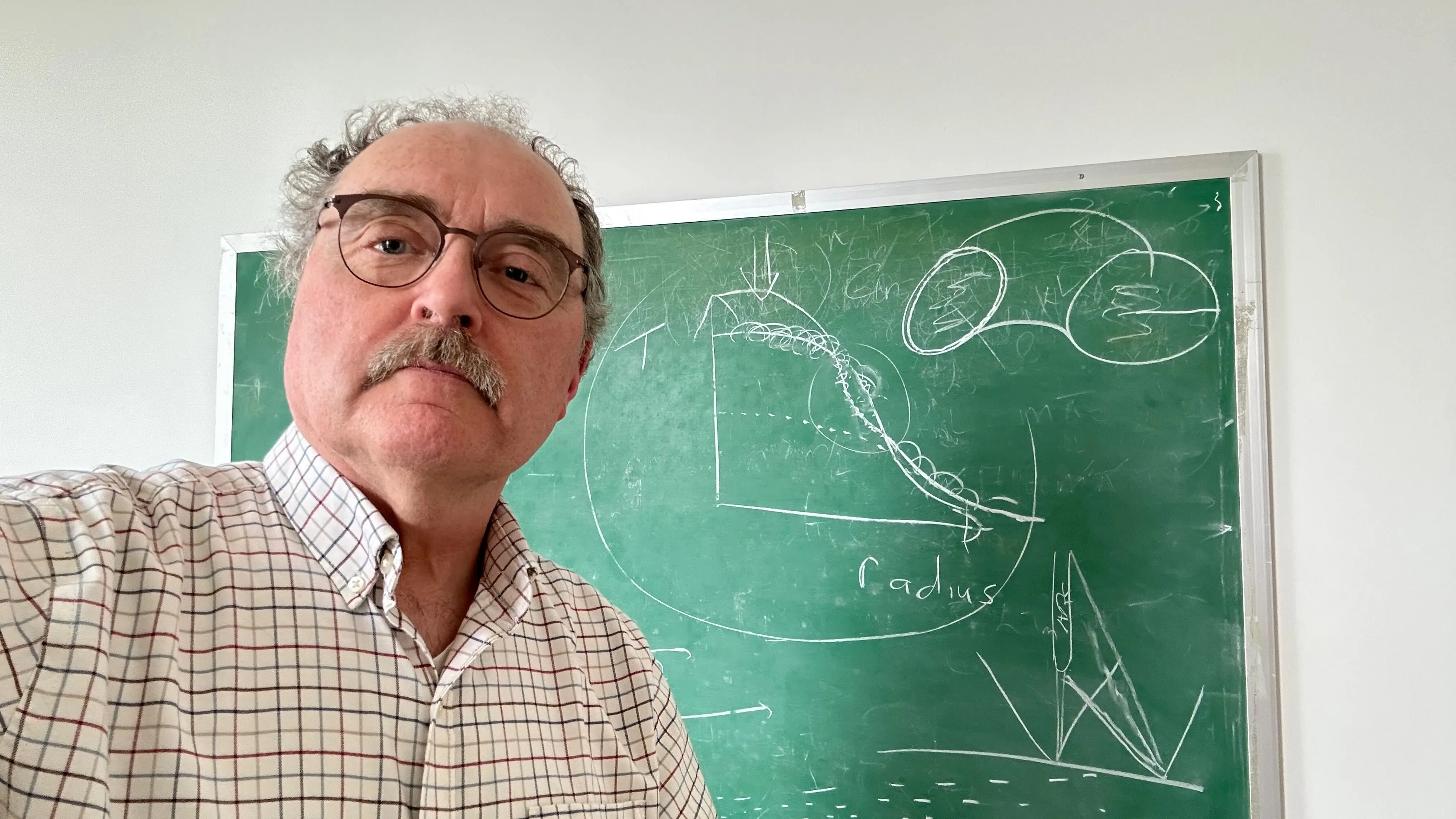 Rod Boyce stands in front of David Newman’s chalkboard sketch made during a discussion of magnetic confinement nuclear fusion. Photo by Rod Boyce.